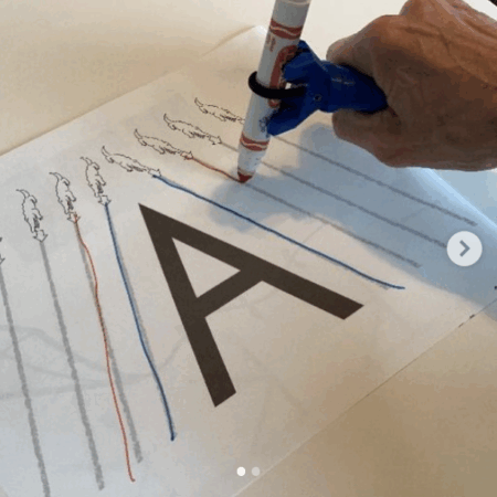 Person using the functionalhand® to trace the letter A while practicing their writing.