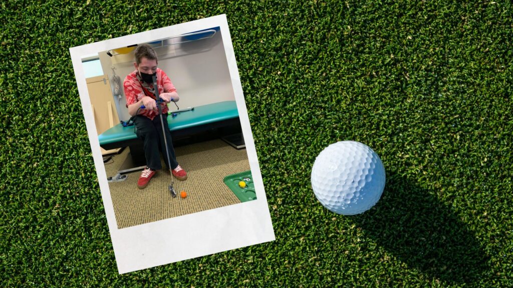 Photo of a boy using two functionalhand® devices to give him a two-handed grasp of a golf putter so he can have better control over his swing and enjoy miniature golf, a traditional summer activity favorite!