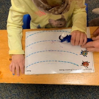 This is an image of a girl tracing a line using the functionalhand and marker with someone assisting by holding the FH.