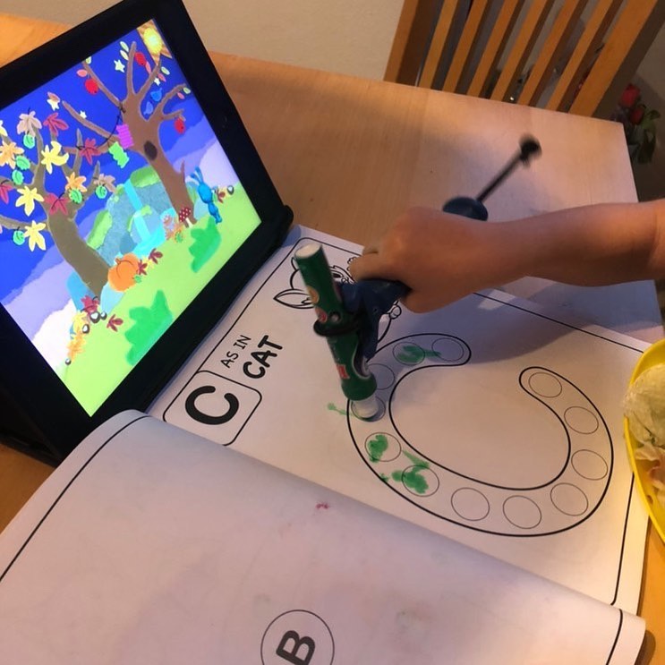 This is a child using the functionalhand with a dot marker to trace a C letter.