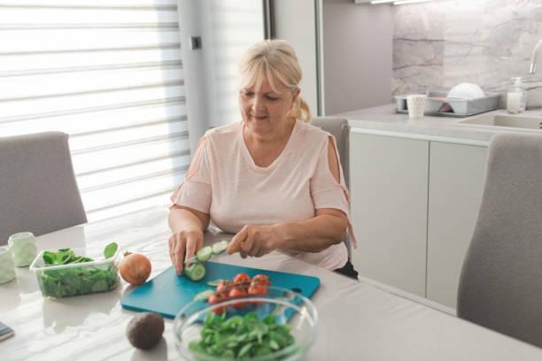 Elder lady cutting vegetable with fatigue